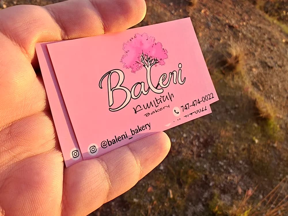 Pink business card with a floral logo and Armenian lettering for Bakeri bakery