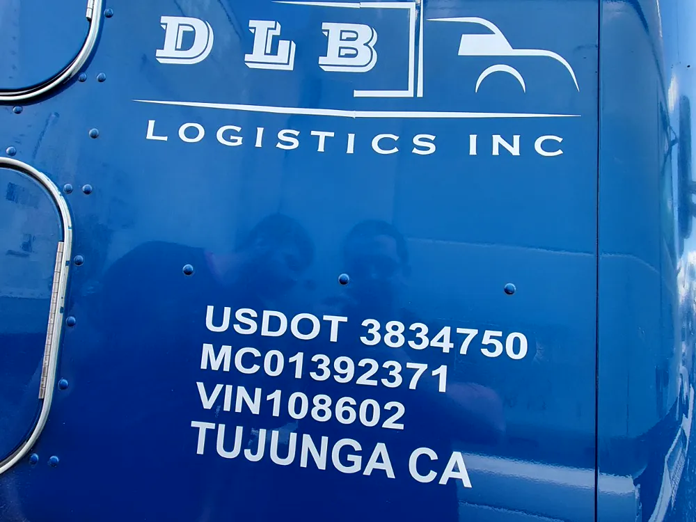 White cut-vinyl USDOT and MC numbers applied to a blue box truck