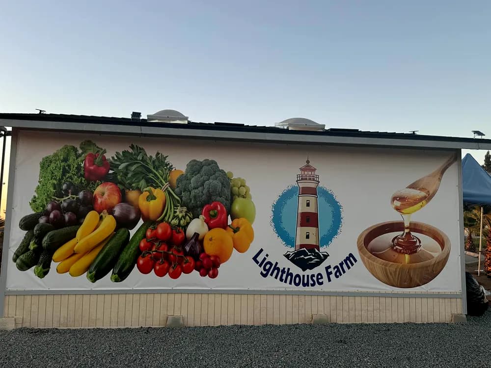 Printed mural covering a farm building wall with fruit, vegetables and honey imagery