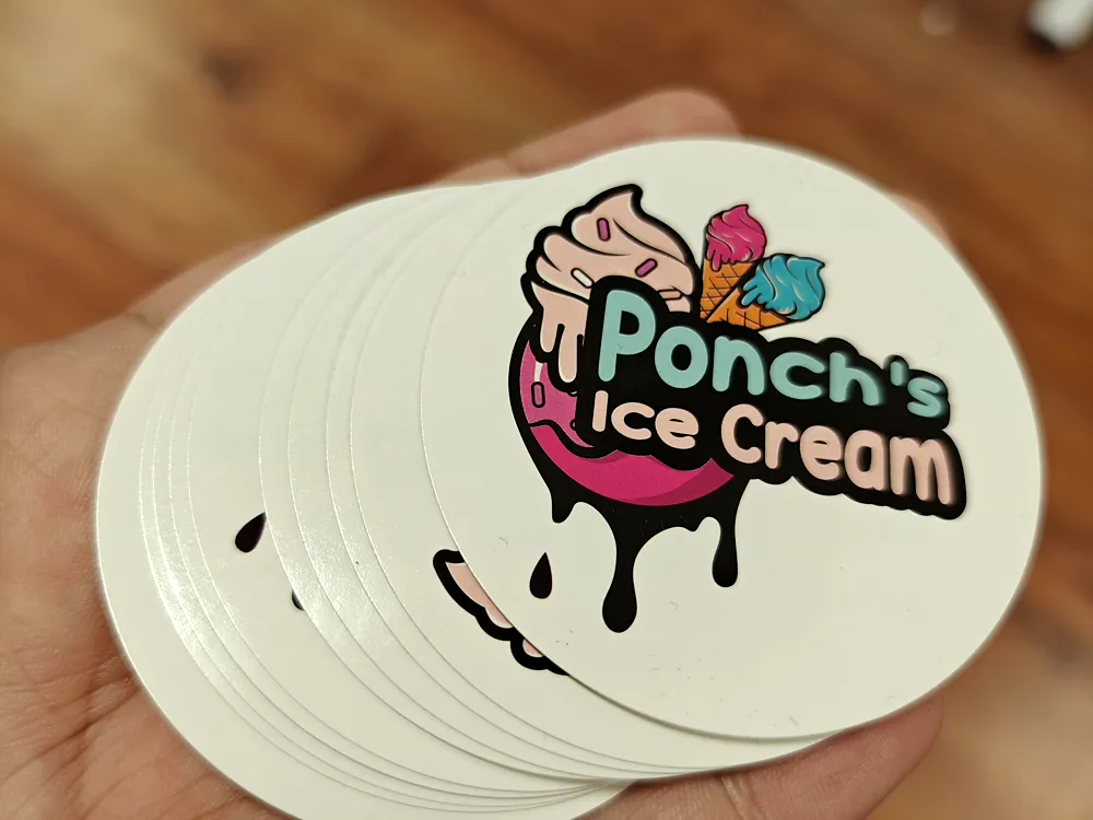Stack of round die-cut stickers with a colourful ice cream logo