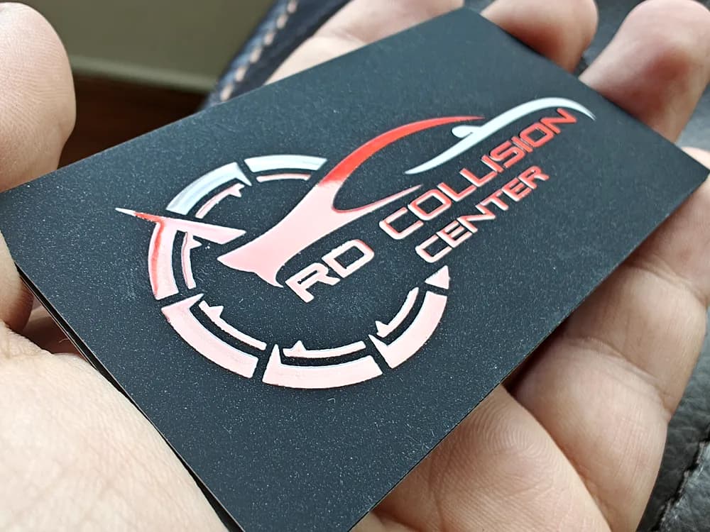 Dark matte business card with a red and white circular collision-centre logo
