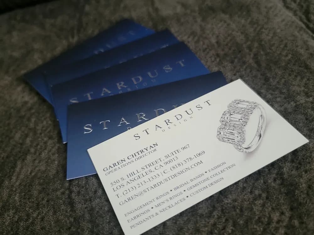 Navy business cards with silver foil lettering and a diamond ring illustration