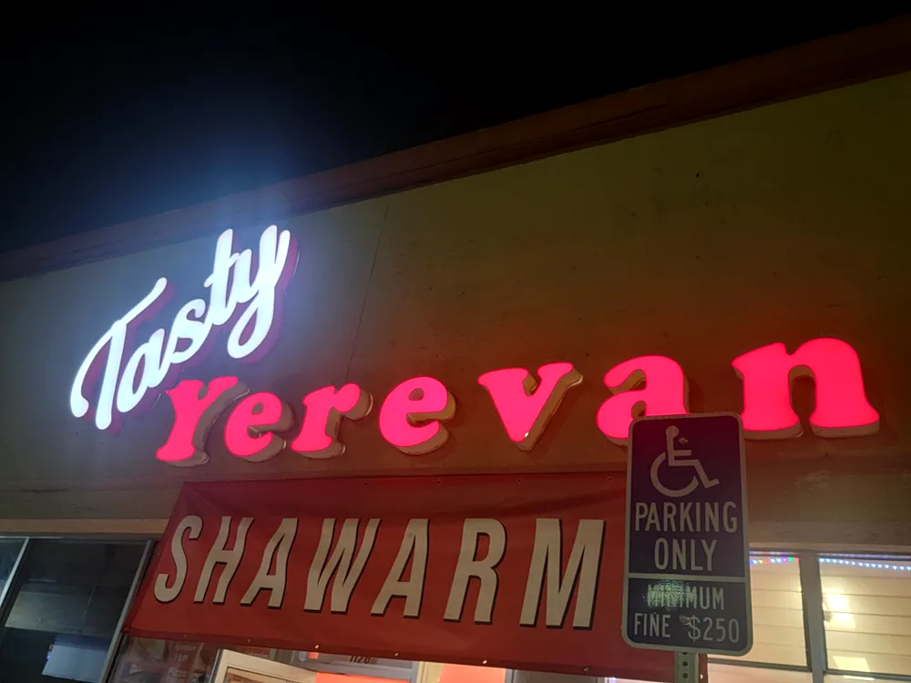 Illuminated pink and white channel-letter storefront sign reading Tasty Yerevan Shawarma at night