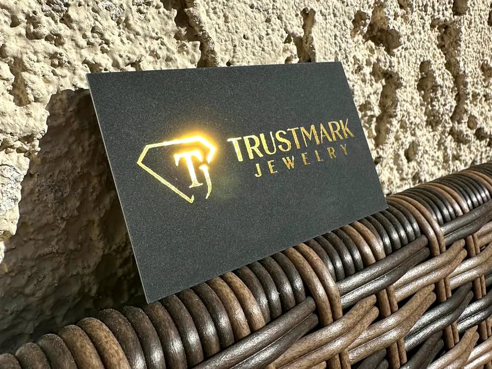Dark brushed metal sign with a gold diamond logo for Trustmark Jewelry