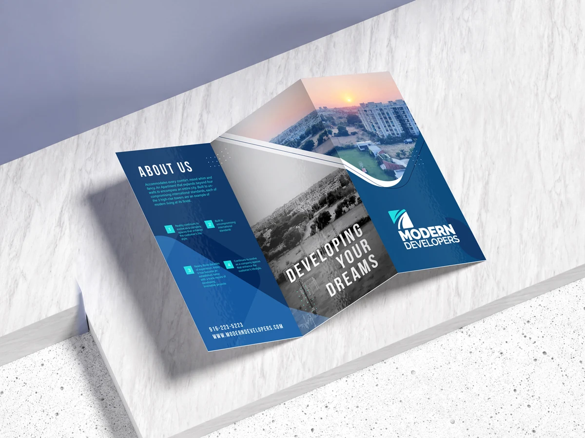 An open tri-fold brochure on a white stone shelf