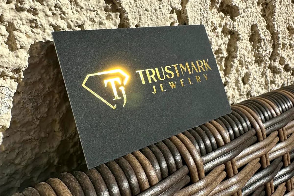 Brushed dark metal sign with a gold foil diamond logo for Trustmark Jewelry
