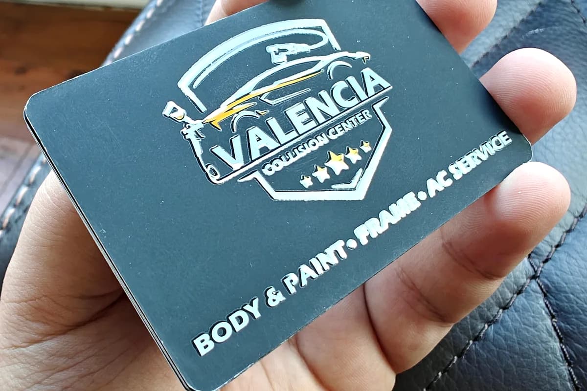 Soft-touch business card with a spot-gloss shield logo for Valencia Collision Center