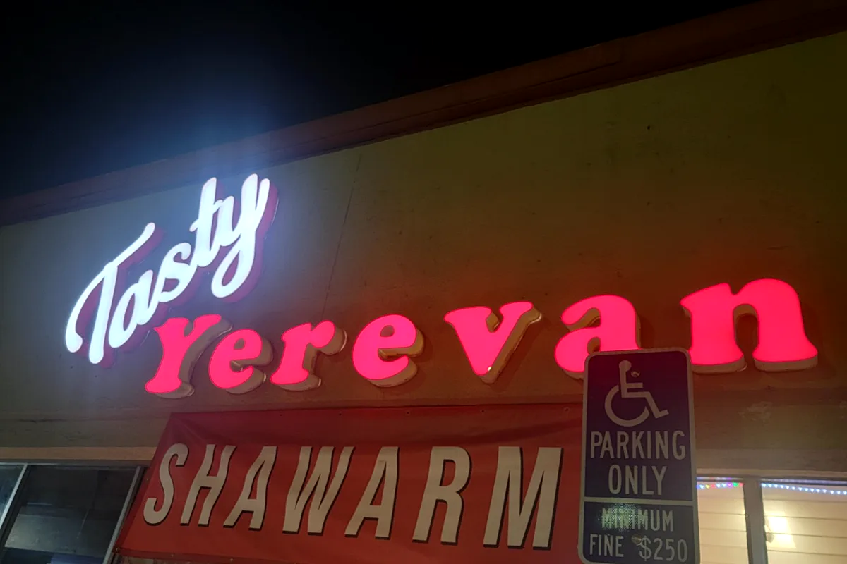 Illuminated channel-letter storefront sign reading Tasty Yerevan Shawarma, lit at night